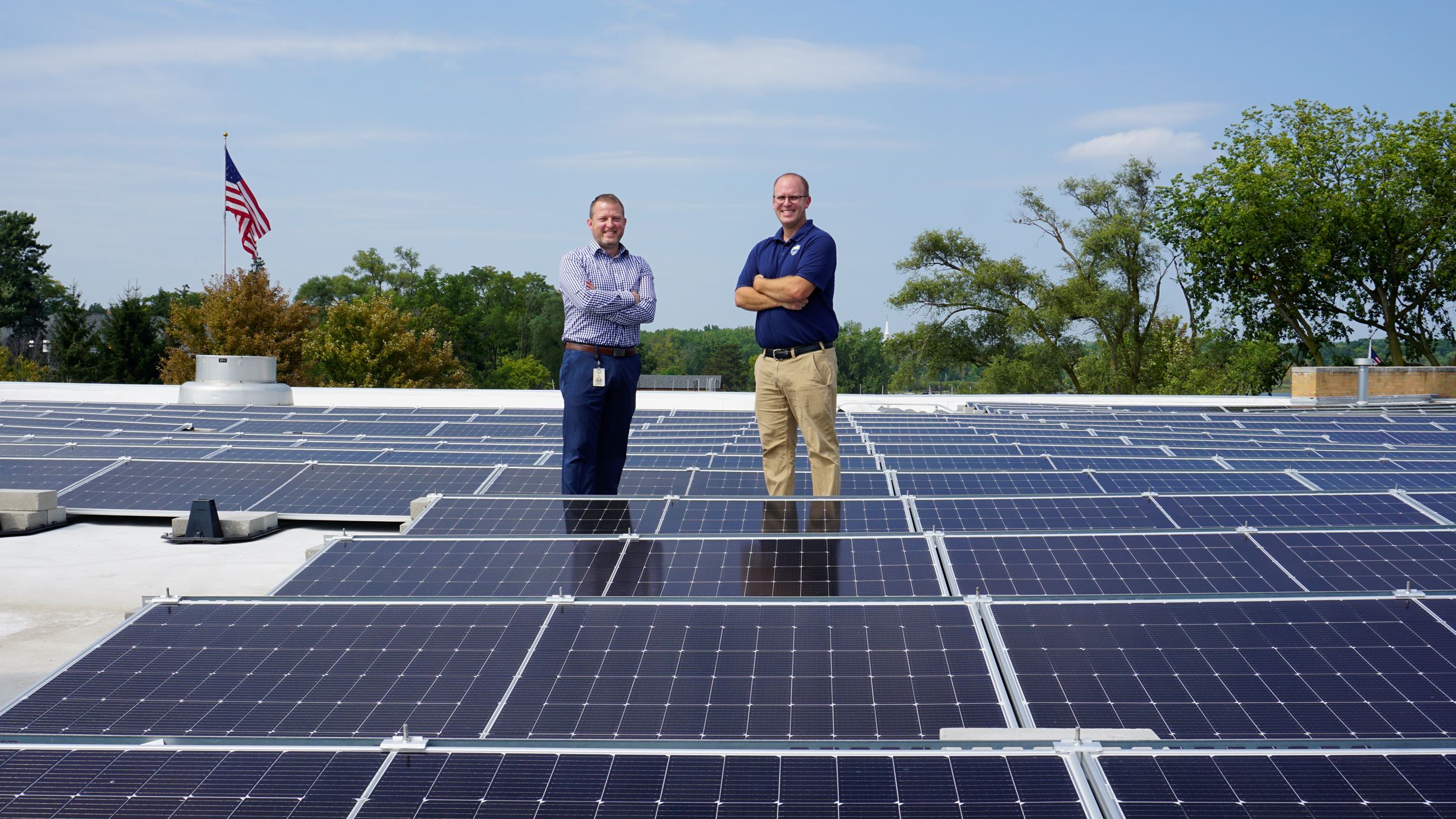Public Works team atop Community Center posing behind solar array
